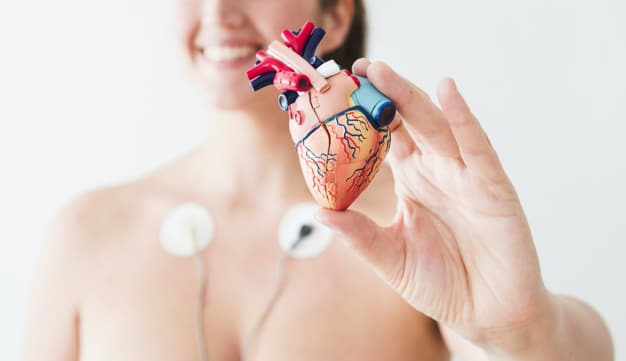 donna con elettrodi che tiene in mano un a figura del cuore